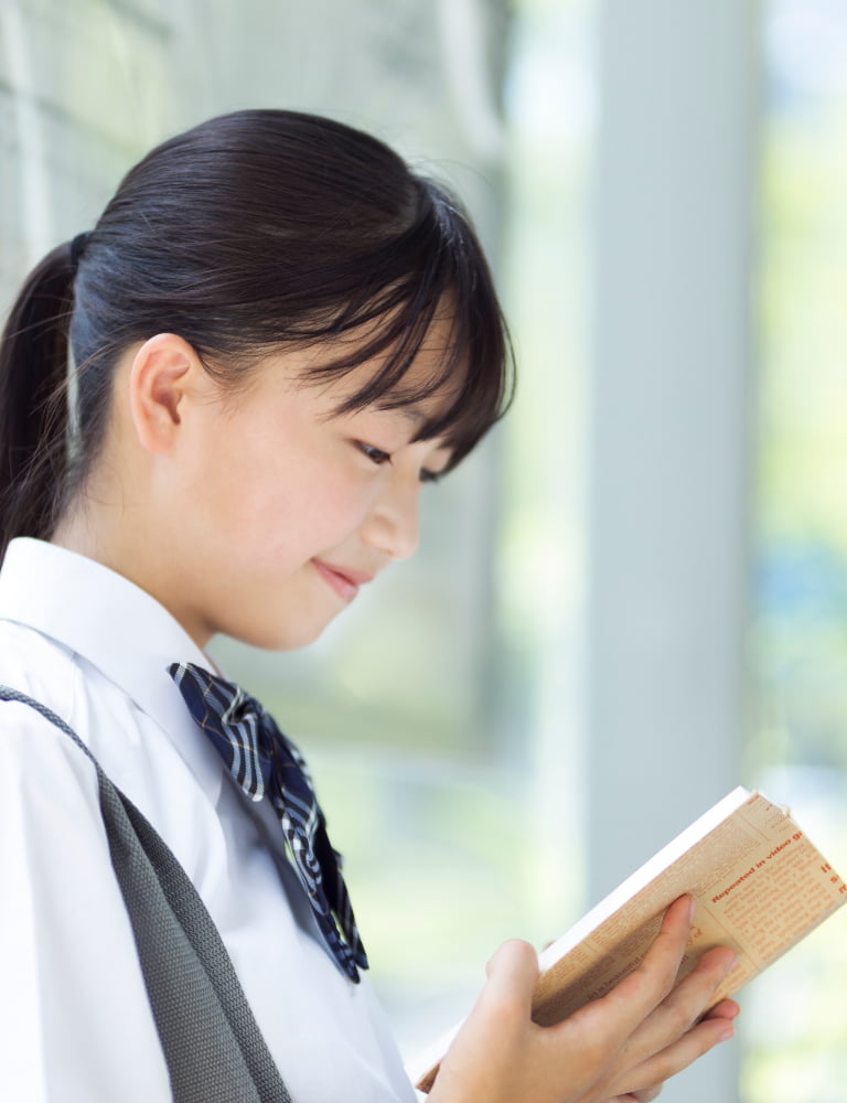 バス停で本を読んでいる女子学生